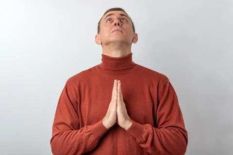 Man with hands clasped in prayer looking upwards, expressing hope, faith, a.. Fotos de archivo