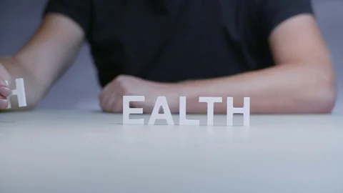 Man hands composition word health from white plastic letter on gray background Stock Footage 82575210