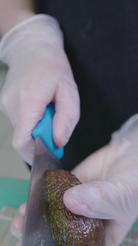 Man hands cut in halves and open ripe avocado on countertop, vertical video Stock Footage 240219760
