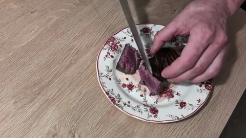 Man hands cutting medium rare steak, tasty meal on handmade flower painted Stock Footage 274264972