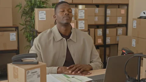 Man with hands on desk and head tilted back, eyes closed, seated at laptop .. Video stock 337434739