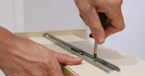 Man hands fix sliding rail onto drawer side using screwdriver Stock Footage 323967292