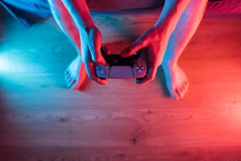 Man hands with game controller in neon light, top view Stock Photos