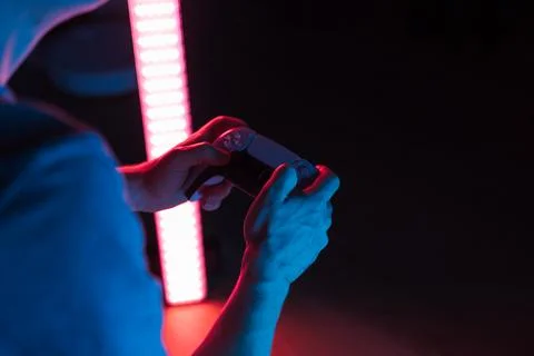 Man hands with game controller in neon light, top view Stock Photos