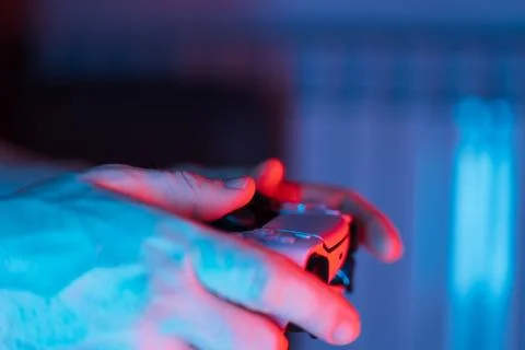Man hands with game controller in neon light, top view Stock Photos