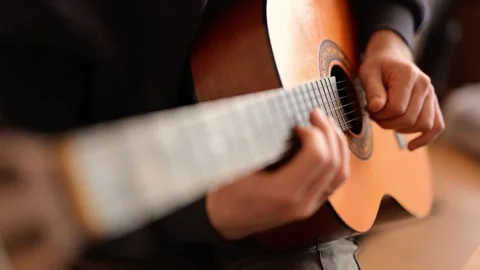 A man hands gently strumming guitar strings in a musical moment. Stock Footage 289410210