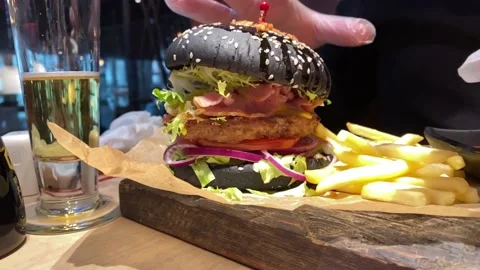 Man hands in gloves going to eat black burger close up. Food truck and street Stock Footage 171173881