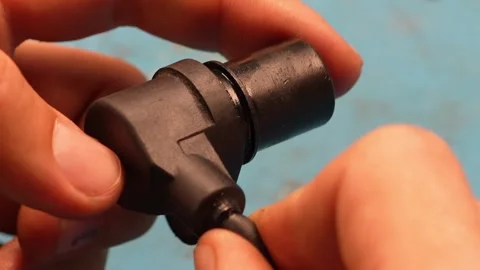 Man hands holding a black plastic car engine crankshaft position sensor. Stock Footage 344593863