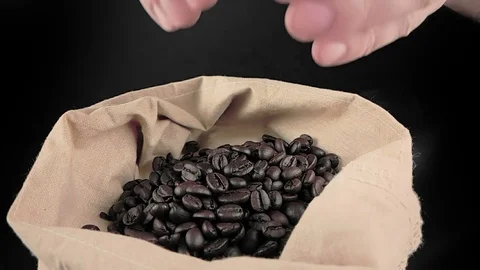 Man hands holding coffee beans in canvas sack and some falling down Stock Footage 77377621