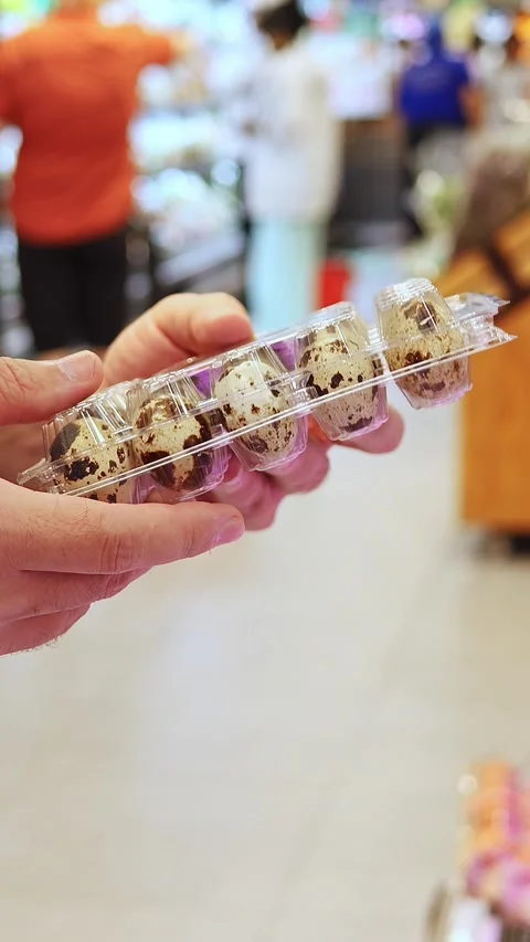 Man hands holding plastic packaging of quail eggs at a grocery store Stock Footage 331600768