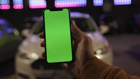 Man hands holding use smartphone with vertical green screen on night city Stock Footage 111600972