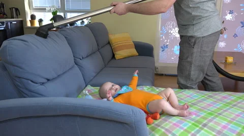 Man hands hoover dust from sofa around baby daughter. 4K Stock Footage 51147514