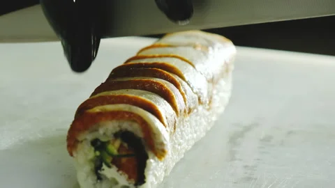 Man hands in latex gloves cut delicious sushi roll on board Stock Footage 324805216
