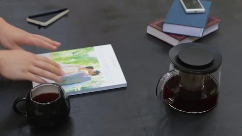 Man hands open book, flipping through pages, reading, drink tea, than closing. Video stock 76969639