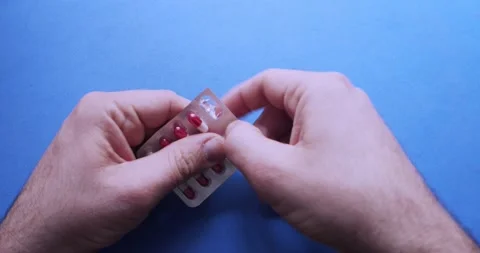 Man hands opening a pill box on a blue background Stock Footage 130776230