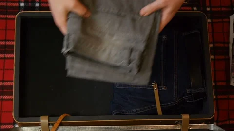Man hands packing suitcase for travel. Top view. Flannel shirt, jeans, electric Stock Footage 108304053