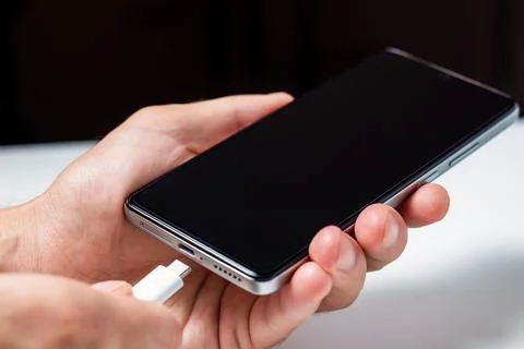 Man hands plugging a charger in a smart phone. Man using smartphone with po.. Stock-Fotos