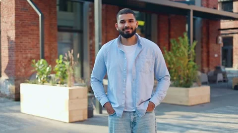 Man with hands in pockets posing at camera against brick building and smiling Stock-Footage 250383966