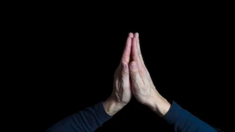 Man hands praying in dark background. Close up. Stock Photos