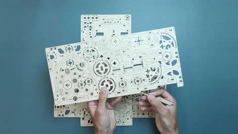Man hands pull out small pieces of puzzle of wooden sheet toy. Mechanical wooden Stock Footage 160928336