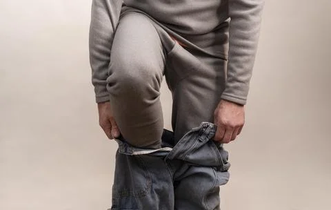 Man hands pulling pants over thermal underwear. Stock Photos