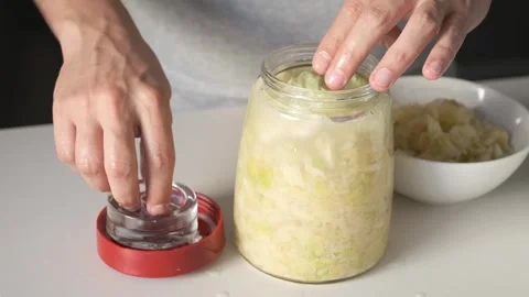 Man hands putting the fermentation weight and closing the jar of sauerkraut. 스톡 동영상 248207154