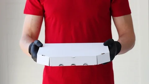 A man hands rubber gloves with a box pizza. Courier. Stock Footage 128986295