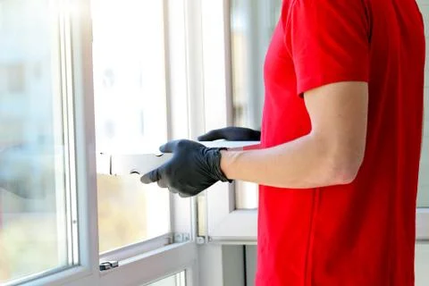 A man hands rubber gloves with a box pizza near the window . Courier. Food de Stock Photos