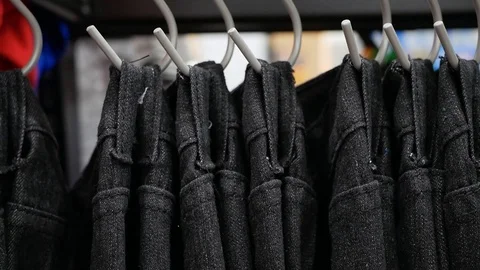 Man hands run across a rack of clothes and chooses the Jean. Stock Footage 121866656