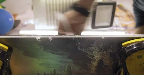 Man Hands With Scraper Scrape The Wax Off The Snowboard. Low Angle Stock Footage 125858865