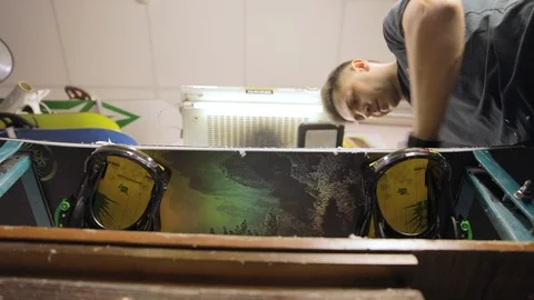 Man Hands With Scraper Scrape The Wax Off The Snowboard. Low Angle. Slow Motion Stock Footage 125858885