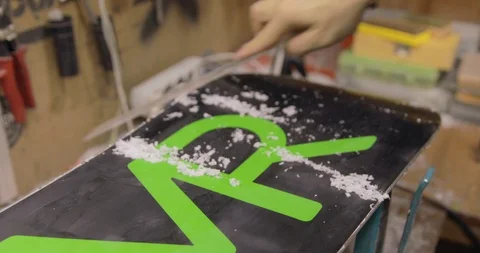Man Hands With Scraper Scrape The Wax Off The Snowboard. Stock Footage 125859022