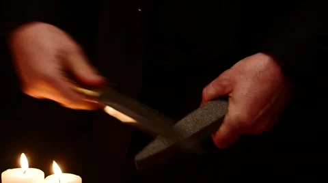 Man hands sharpening battle knife on black background with candles hd Stock Footage 45909710