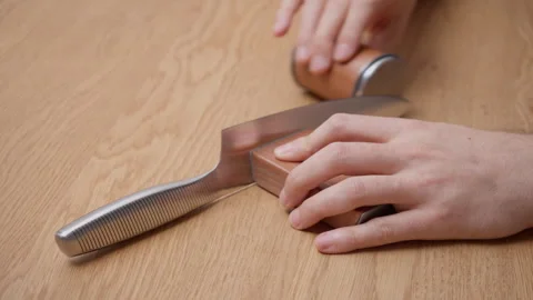 Man hands sharpening kitchen chef knife using rolling sharpener with sound Stock Footage 327647827