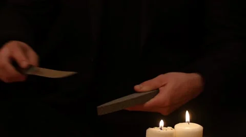 Man hands sharpening  knife on black background with candles 4k Stock Footage 45819311