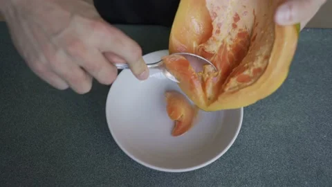 Man hands sing a spoon to carefully slice a papaya HLG3, BT.2020 Video stock 231173116