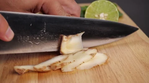 Man hands slice galangal in pieces on cutting board with other Thai herbs Stock Footage 141018434