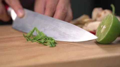Man hands slice Kaffir lime leaves in pieces on cutting board Stockbeeldmateriaal 141017274