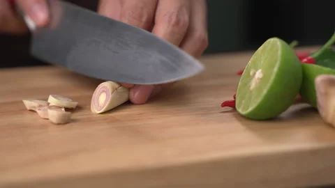 Man hands slice lemon grass in pieces on cutting board with other Thai herbs Stock Footage 141016314