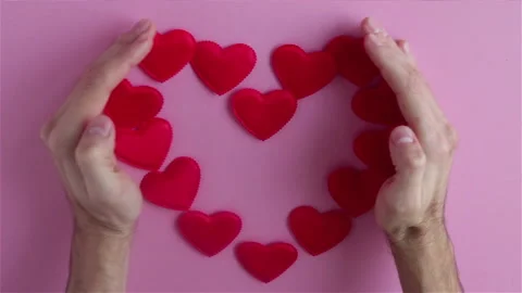 Man hands with small red heart shapes on pink background happy valentines day Stock Footage 121326571
