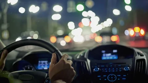 Man hands on steering wheel. Driving car in evening city through traffic jam Stock Footage 224152489