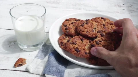 Man hands take a chocolate cookie and glass of milk on white table Stock Footage 114211969
