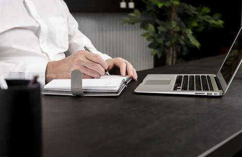 Man hands taking notes in planner. Businessman sitting at table with laptop and Stock Photos