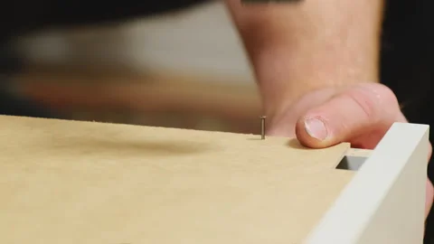 Man hands tap on nail head with hammer fastening dresser parts Stock Footage 304397641