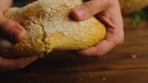 Man hands tearing fresh bread on a half. Male hands breaking whole grain bread Stock Footage 74753666