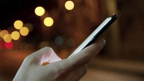 Man hands texting on a smartphone in the night city on background.Connecting and Stock-Footage 128033230