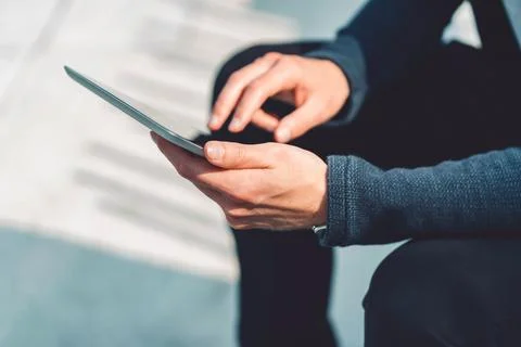 Man hands typing on digital tablet while sitting outside on a sunny day Stock Photos