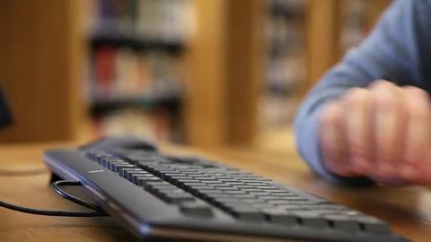Man Hands Typing On A Keyboard in a Library Stock Footage 85881670