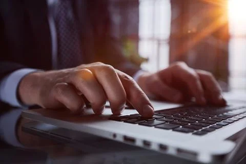 Man hands typing on laptop computer keyboard and surfing the internet on office Stock Photos