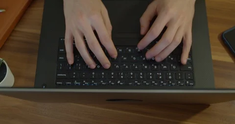 Man hands typing text on laptop keyboard at wooden desk. Man using notebook for Stock Footage 129460123